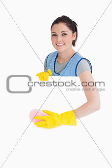 Cheerful maid washing with a sponge