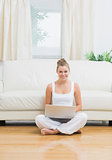 Joyful woman sitting on the floor with laptop