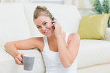 Cheerful woman drinking coffee while calling