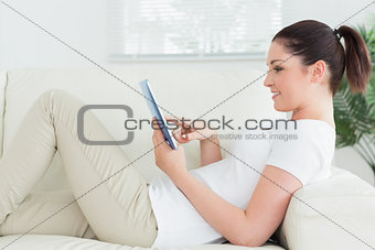 Lying woman on the couch using a tablet pc