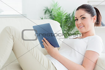 Woman lying on the couch and using a tablet computer