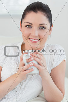 Happy woman on the couch holding a cup