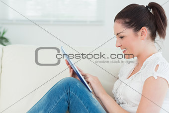 Happy woman using a tablet pc and sitting on the couch