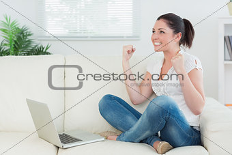 Woman using a laptop on the couch and being happy