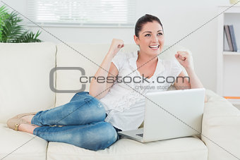 Woman lying on the couch and using a laptop