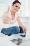 Woman using a laptop and giving thumbs up