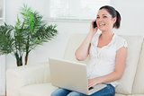 Phoning woman on the couch using a laptop