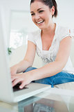 Laughing woman on the couch using a laptop