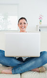 Woman sitting cross-legged on a couch and using a laptop