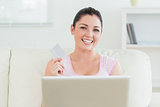 Smiling woman using a laptop and holding a credit card