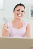 Woman sitting on a couch with a laptop and a credit card