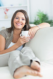 Happy woman drinking a mug on the sofa