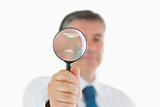 Businessman holding up magnifying glass
