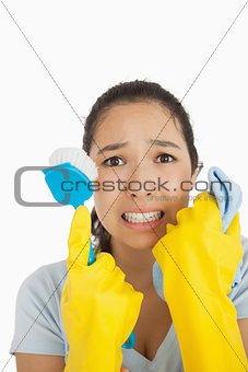 Stressed woman holding scrubbing brush and rag