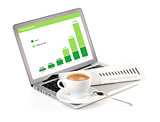Laptop with chart, cappuchino cup and newspaper