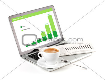 Laptop with chart, cappuchino cup and newspaper