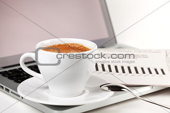 Cappuccino cup with laptop and newspaper