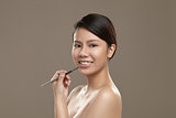 Female asian applying lipgloss