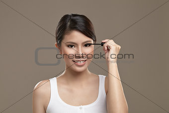Female asian applying mascara