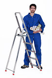 Man stood by ladder holding selection of wallpaper rolls