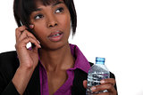 A black businesswoman on the phone waiting to take a sip.