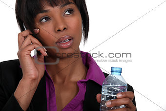 A black businesswoman on the phone waiting to take a sip.