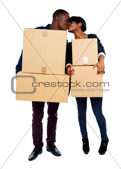 Couple holding cardboard boxes and kissing