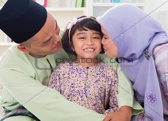 Muslim parents kissing child.