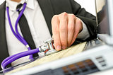 Close up of repairman holding stethoscope of laptop keyboard