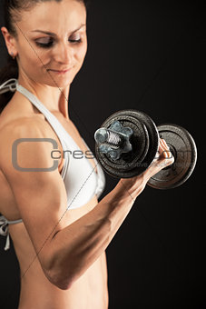 Muscular young woman lifting a dumbbell