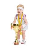 Happy baby in tennis clothes holding medal and goblet
