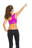 Fitness young woman pointing on copy space . rear view