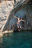 Man jumping from cliff into sea