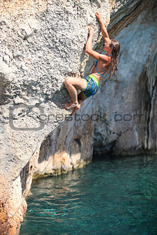 Deep water soloing, female rock climber on cliff