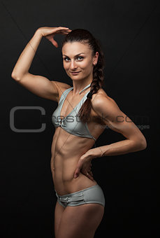 Fitness woman in bikini flexing bicep