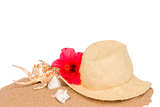 straw hat ans seashells on sand