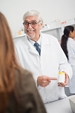 Smiling male pharmacist pointing at drugs