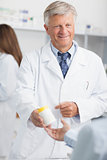 Pharmacist holding a box of pills while pointing at it