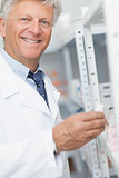 Smiling pharmacist looking at pills in a shelf