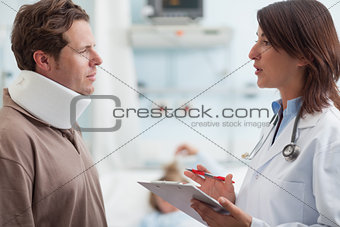 Doctor talking to a male patient with a collar on