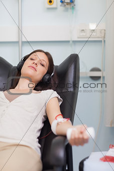 Female patient listening to music while giving her blood in a hospital