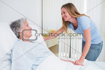 Smiling woman holding the hand of a patient in a room