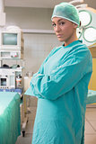 Female surgeon crossing her arms while standing next to an operating table