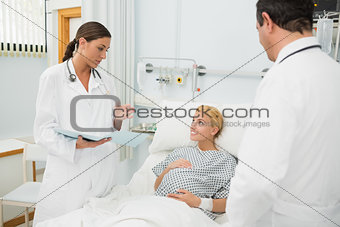 Male and female doctor standing next to a patient