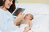 Mother using a tablet to take a picture of a newborn baby