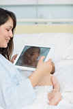 Happy mother using a tablet to take a picture of a newborn baby