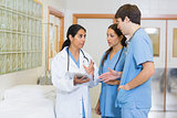 Female doctor talking to a male and a female nurse in a hallway