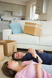 Happy couple lying on floor with moving boxes