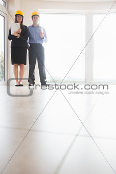 Woman and man holding blueprint and clipboard