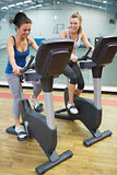 Two laughing women on exercise bikes